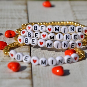 Pulseira delicada de miçangas douradas com letras Be Mine e corações