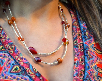 May include: A double-strand necklace with small white beads and larger red, orange, and brown beads.