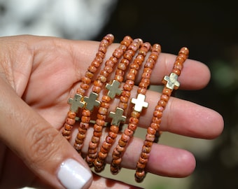 Delicada pulsera de cuentas de semillas de oro rosa con una pequeña cruz dorada. Pulsera de Pascua, pulsera cristiana y pulsera de fe.