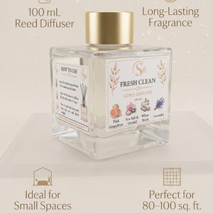 May include: A square glass reed diffuser bottle with a gold cap and a white label reading Fresh Clean Home Diffuser 100 mL. The label features illustrations of pink grapefruit, sea salt, orchid, white birch, and lavender. Text includes 100 mL Reed Diffuser, Long-Lasting Fragrance, Ideal for Small Spaces, and Perfect for 80-100 sq. ft.