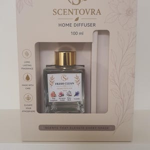 May include: A Scentovra home diffuser set in a beige box with floral line art. The 100 ml glass bottle has a gold cap and a label reading Fresh Clean Home Diffuser with icons of Pink Grapefruit, Sea Salt & Orchid, White Birch, and Lavender.
