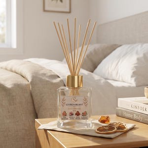 May include: A clear glass home diffuser bottle with a gold cap and wooden reeds. The label reads Citrus Blast Home Diffuser 100ml, featuring illustrations of pink grapefruit, sea salt, orchid, amber, and mangosteen. Two dried orange slices sit nearby.