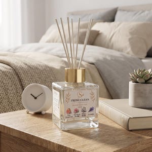 May include: A square glass home diffuser with a gold-toned cap and several wooden reeds. The label features the text FRESH CLEAN HOME DIFFUSER and illustrations of pink grapefruit, sea salt, orchid, white birch, and lavender with a 100 ML label.