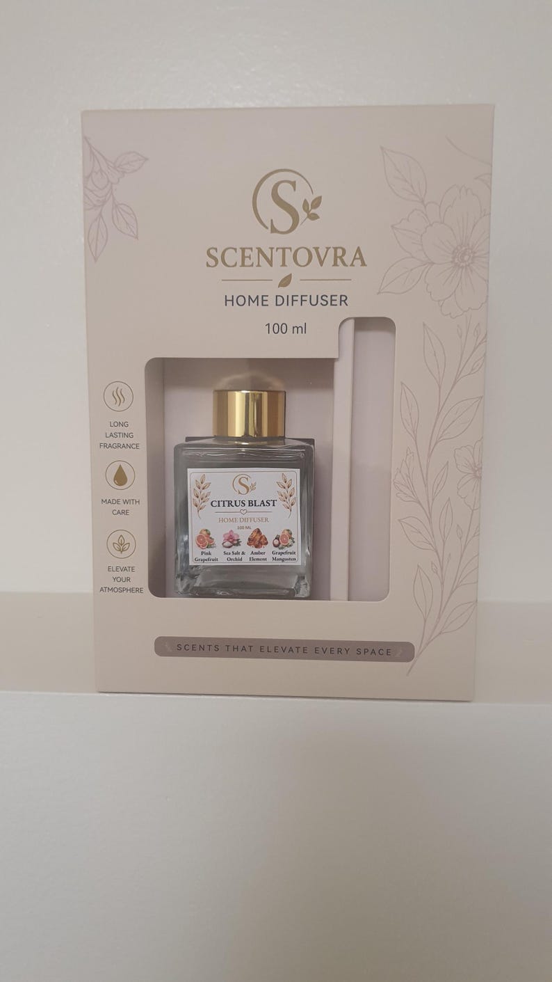 May include: A Scentovra Citrus Blast home diffuser set in a beige box with floral line art. The square glass bottle has a gold cap and a label listing Pink Grapefruit, Sea Salt & Amber, Orchid Element, and Mangosteen. The box states 100 ml.