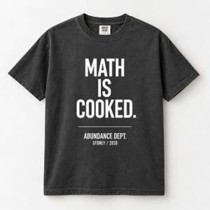 May include: A charcoal grey short-sleeved t-shirt featuring the white text "MATH IS COOKED." centred on the chest, with "ABUNDANCE DEPT. SYDNEY / 2026" printed below a horizontal line. The garment has a crew neckline and a vintage-washed finish.