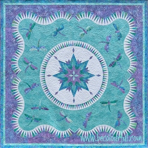 May include: A teal blue quilt with a white starburst design in the center. The quilt is surrounded by a border of purple and blue fabric with a scalloped edge. The quilt is decorated with dragonfly designs throughout.