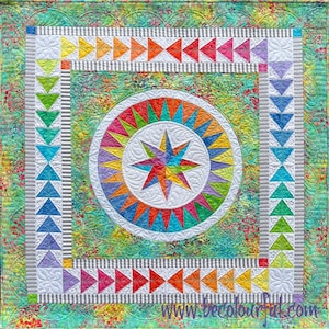 May include: A colorful quilt with a starburst design in the center. The quilt is surrounded by a border of triangles in various colors. The quilt is made with a variety of fabrics, including a green and white floral fabric. The quilt is quilted with a white thread. The quilt is signed "www.becolourfull.com".