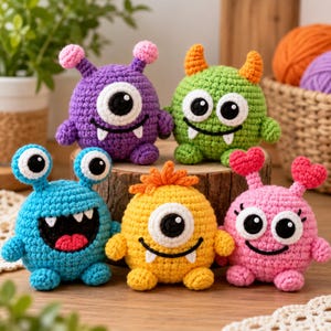 May include: Five small, round, crocheted monster toys in purple, green, blue, yellow, and pink. Each monster features distinct facial expressions, including large white eyes with black pupils, small horns or antennae, and white fangs or smiles.