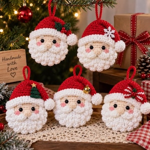 Puede incluir: Cinco adornos navideños de ganchillo con forma de Papá Noel, con gorros rojos y barbas blancas. Cada gorro tiene un detalle único: bayas de acebo, un copo de nieve blanco, un pequeño árbol verde, un cascabel dorado o un lazo a cuadros.