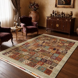 Può includere: Un tappeto rettangolare caratterizzato da un design patchwork multicolore con intricati motivi geometrici e floreali nelle tonalità del rosso, blu, verde e crema, rifinito con un bordo chiaro e frange corte sui lati.
