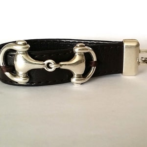 May include: A brown leather key chain with a silver horse bit charm and a silver key ring.