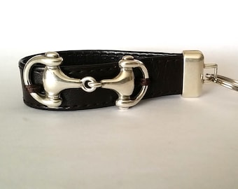 May include: A brown leather key chain with a silver horse bit charm and a silver key ring.