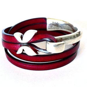 May include: A red leather wrap bracelet with a silver butterfly charm and a silver clasp.