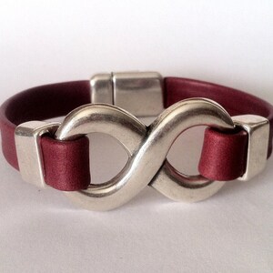 May include: A burgundy leather bracelet with a silver infinity symbol clasp.