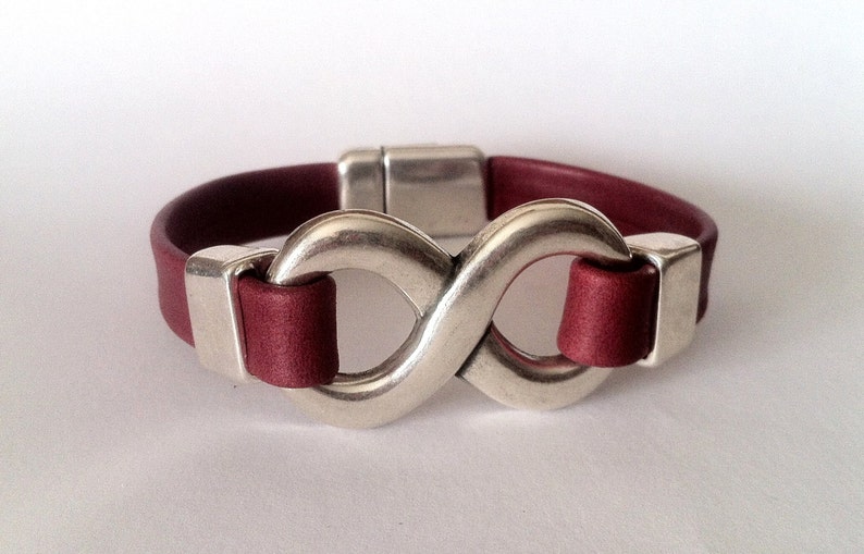 May include: A burgundy leather bracelet with a silver infinity symbol clasp.
