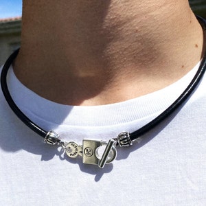 May include: A black leather choker necklace with a silver clasp featuring the text "24" and "MADE IN ITALY".