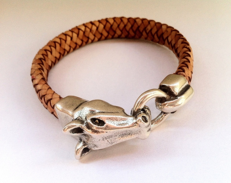 May include: A braided leather bracelet with a silver horse head clasp.