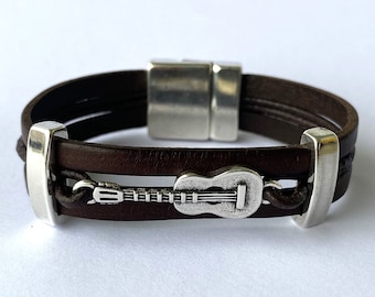 May include: A brown leather bracelet with a silver guitar charm and a silver magnetic clasp.