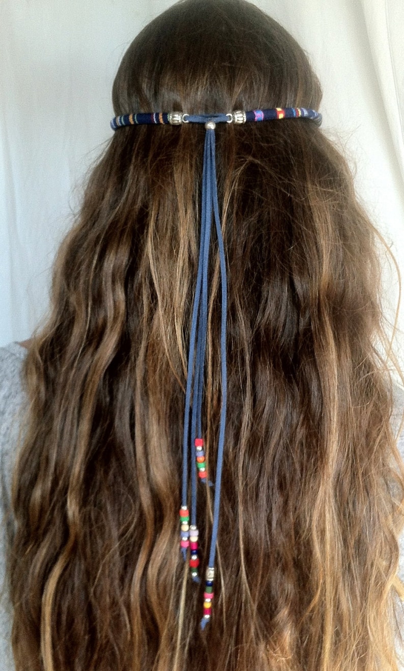 Puede incluir: Una diadema de cuentas azules y blancas con una larga borla de gamuza azul y cuentas de colores que cuelgan.