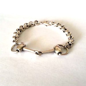 May include: A silver bracelet with a chain link design and a snaffle bit clasp.