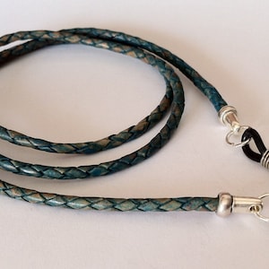 May include: A teal blue leather eyeglass chain with silver metal clasps and black rubber tips.