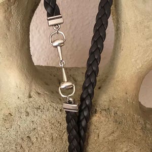May include: A brown leather braided key chain with a silver horse bit charm and a silver key ring.
