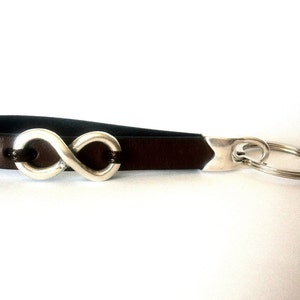 May include: Brown leather keyring with a silver infinity symbol charm and a silver key ring.