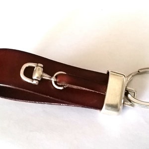 May include: A brown leather key chain with a silver horse bit charm and a silver key ring.