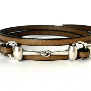 May include: A brown leather bracelet with a silver equestrian bit charm.