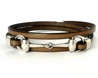 May include: A brown leather bracelet with a silver equestrian bit charm.