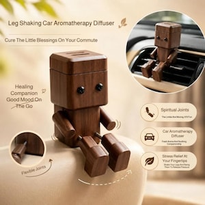 May include: A dark brown wooden robot-shaped car aromatherapy diffuser with a square head, two black dot eyes, and movable limbs. The text reads Leg Shaking Car Aromatherapy Diffuser, Cure The Little Blessings On Your Commute, Healing Companion Good Mood On The Go, Spiritual Joints, and Stress Relief At Your Fingertips.
