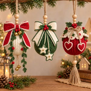 May include: Three round crocheted Christmas ornaments hanging from twine with wooden beads. The first is cream with a red bow and green vines. The second is green with a cream bow and star accents. The third is red with a cream lace top and hearts.
