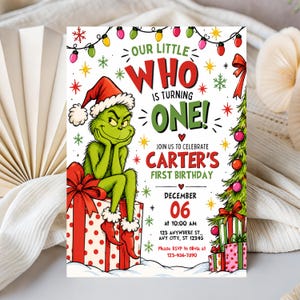 May include: A birthday invitation card featuring a green character in a Santa hat sitting on a red and white polka dot gift box. Text reads: Our Little Who Is Turning One! Join us to celebrate Carter's First Birthday, December 06 at 10:00 AM.