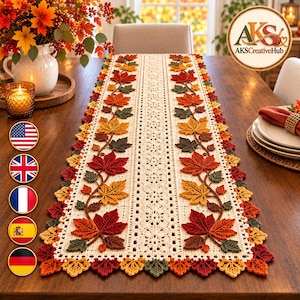 Pode incluir: Um caminho de mesa retangular de crochê na cor creme, com um padrão central de renda ladeado por duas fileiras verticais de folhas de bordo de outono tridimensionais em tons de vermelho, laranja, amarelo e verde escuro, com borda festonada.