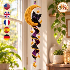 May include: A hanging crochet decoration featuring a black cat with purple eyes resting on a yellow crescent moon. Below the moon, a spiral tail in black and purple yarn hangs down, accented with small yellow crochet stars and purple beads.