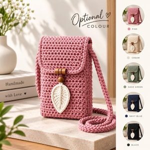 Può includere: Una borsa a tracolla all'uncinetto rosa con chiusura a patta, una lunga tracolla intrecciata e un ciondolo decorativo a forma di foglia bianca sospeso da due perline di legno. Il pannello laterale mostra i colori rosa, crema, verde salvia, blu navy e nero.