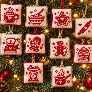 May include: A collection of ten square, cream-coloured fabric ornaments featuring red cross-stitch embroidery designs. The motifs include a steaming mug, a mixing bowl, a star, a rolling pin, a kettle, a mitten, a gingerbread person, a jar, a scale, and a pot.