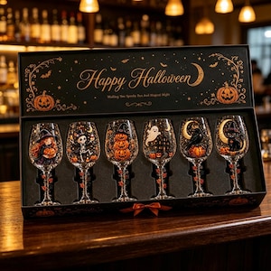 May include: A black gift box containing six wine glasses with Halloween-themed illustrations. The box lid features the text Happy Halloween and Wishing You Spooky Fun And Magical Night. Each glass displays unique designs including a witch, skeleton, pumpkins, ghost, raven, and black cat.