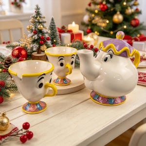 May include: A ceramic teapot and two matching cups featuring character faces with large eyes and eyelashes. The teapot has a purple lid with yellow trim, while the cups have yellow rims and handles. The bases are decorated with pink and blue petals.