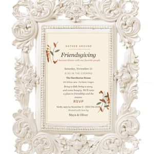 Op de afbeelding: Een crèmekleurige, sierlijke fotolijst met gedetailleerde krulwerkdetails met een Friendsgiving-uitnodiging. De tekst luidt: Gather Around Friendsgiving, A harvest dinner with our favorite people, Saturday, November 21, 6:30 PM.
