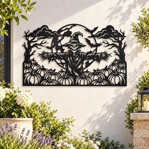 Op de afbeelding: Een zwart metalen wanddecoratie met een centrale vogelverschrikkerfiguur met een hoed met brede rand, geplaatst voor een grote volle maan. De scène bevat silhouetten van kale bomen, vliegende vleermuizen, wolken en een veld met pompoenen.