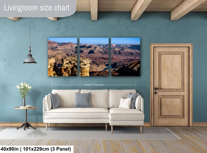 May include: A three-panel canvas wall art set depicting a Grand Canyon landscape with rocky cliffs and a blue sky. The artwork is displayed above a cream-colored sectional sofa. Text on the image includes Livingroom size chart and 40x90in.