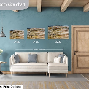 May include: A living room size chart displaying three rectangular landscape wall art prints above a cream-colored sectional sofa. The prints show a rocky, layered geological formation. Sizes listed are 16x24 inches, 20x30 inches, and 24x36 inches.