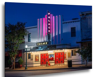 May include: A night view of the Palace theater building featuring a vertical neon sign with the word PALACE in pink, a marquee displaying 42ND STREET, and bright red double doors. The white facade is illuminated against a deep blue sky.