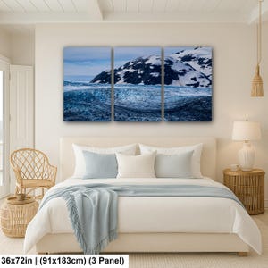 May include: A three-panel wall art set depicting a snowy mountain landscape with a dark blue glacier in the foreground. The artwork measures 36 by 72 inches and features a high-contrast scene of white snow-capped peaks against a blue sky.