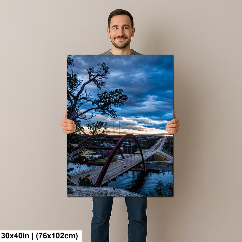 May include: A rectangular wall art print measuring 30 by 40 inches, featuring a landscape photograph of a large arched bridge spanning a river at dusk. The scene includes a dark, cloudy blue sky, silhouetted trees, and a highway with visible traffic.