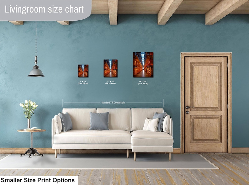 May include: A living room size chart displaying three rectangular wall art prints in sizes 8x10 inches, 11x14 inches, and 16x20 inches, positioned above a cream-colored sectional sofa. The prints feature a perspective view of a library interior.