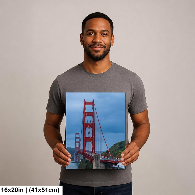 May include: A rectangular wall art print featuring a vertical perspective of the Golden Gate Bridge in San Francisco. The iconic red-orange suspension bridge spans across blue water under a cloudy sky, measuring 16 inches by 20 inches in size.