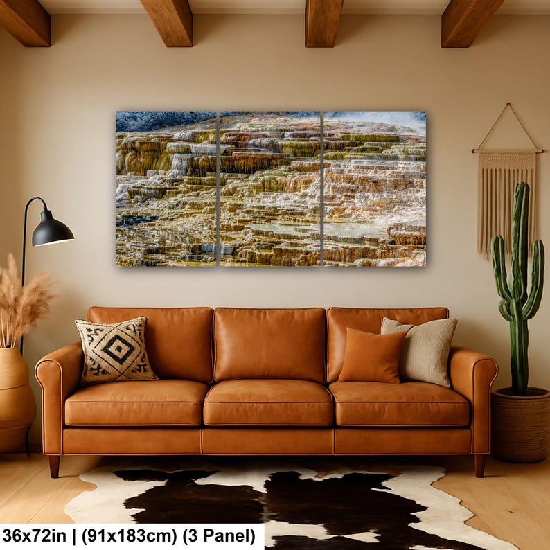 May include: A three-panel wall art set depicting a landscape of layered mineral terraces in shades of orange, brown, and white. The artwork measures 36 by 72 inches and is displayed above a brown leather sofa in a living room setting.