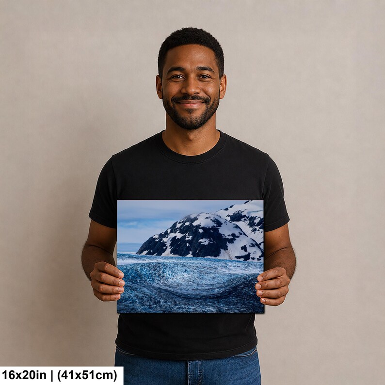 May include: A rectangular wall art print measuring 16 by 20 inches, featuring a landscape photograph of a dark blue, textured glacial ice formation in the foreground with snow-capped mountains under a pale sky in the background.